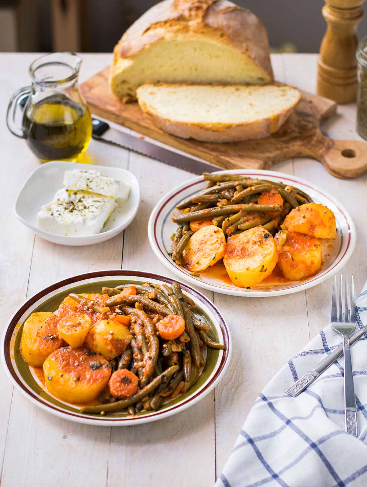 Δύο πιάτα με φασολάκια λαδερά με πατάτες, ψωμί και φέτα.
